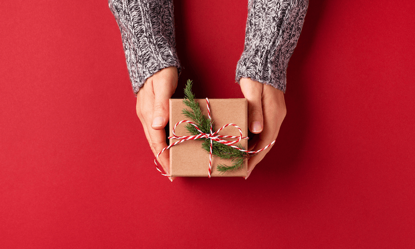 a red background with hhands holding a wrapped present