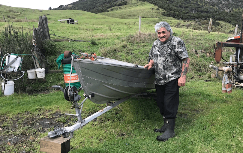A man is smiling next to his boat.