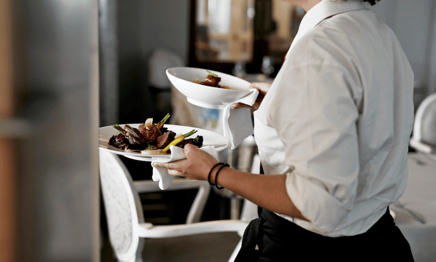 Waiter walking with dishes inside restaurant