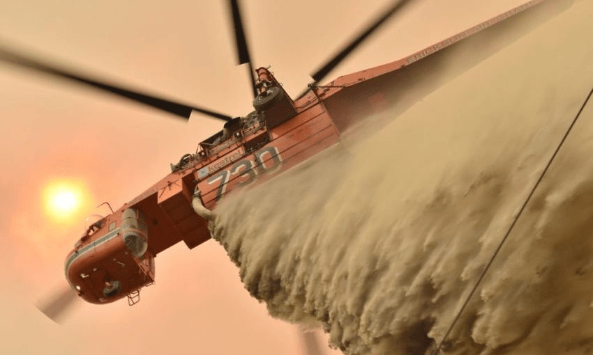 A helicopter drops fire retardant to protect a property in New South Wales. (Photo by PETER PARKS/AFP via Getty Images) 
