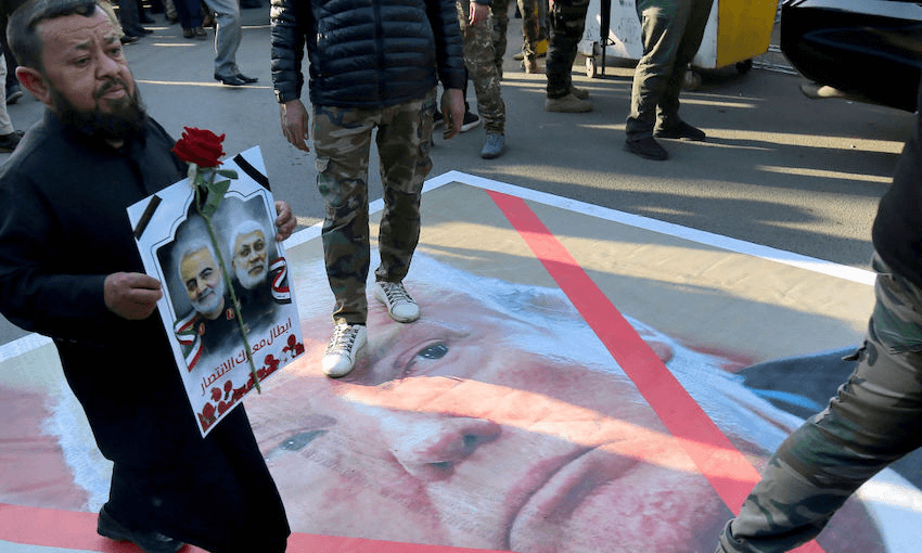 An Iraqi man walks above a portrait of US President Donald Trump following the killings of Iranian commander Qassem Soleimani and Iraqi paramilitary commander Abu Mahdi Al-Muhandis, on January 6, 2020 in Karrada in central Baghdad (Photo by AHMAD AL-RUBAYE/AFP via Getty Images) 
