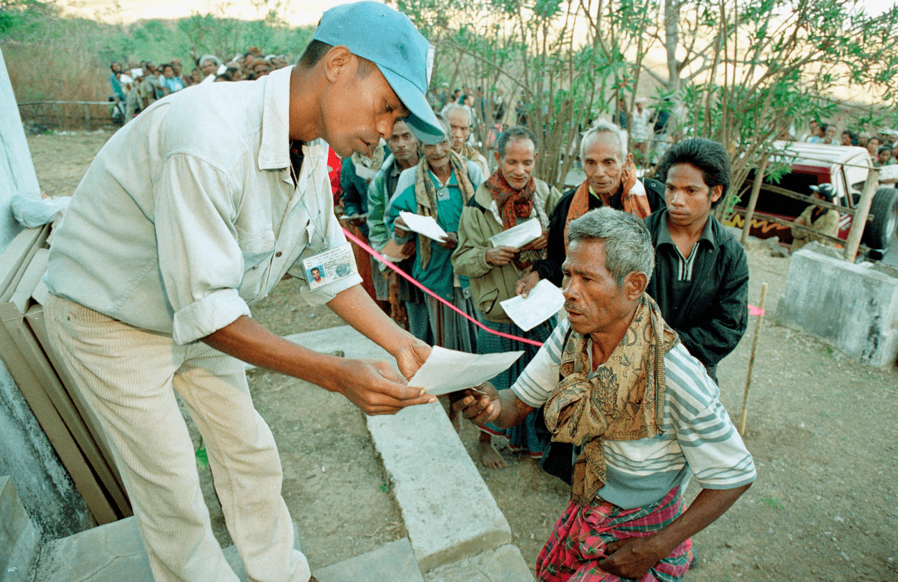 A Unamet Election Offical Leads The First Man Into The Polling Station in East Timor on Voting Day, 1999. Photo: Bronstein/Getty Images 
