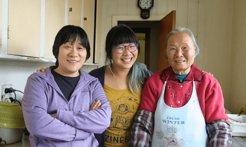 “Lu traces the changing dreams and expectations of three generations”. Rose with her mother and bu’uah in the kitchen of their Whanganui home, 2016. Supplied. 
