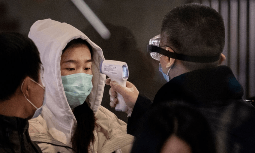 A Chinese passenger that just arrived on the last bullet train from Wuhan to Beijing is checked for a fever by a health worker at a Beijing railway station on January 23, 2020 in Beijing (Photo by Kevin Frayer/Getty Images) 
