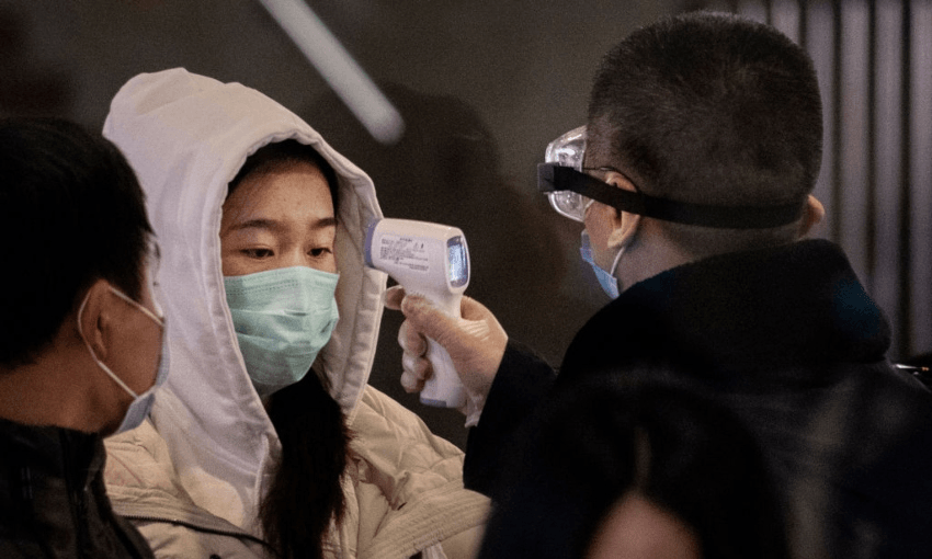 A Chinese passenger that just arrived on the last bullet train from Wuhan to Beijing is checked for a fever by a health worker at a Beijing railway station on January 23, 2020 in Beijing (Photo by Kevin Frayer/Getty Images)