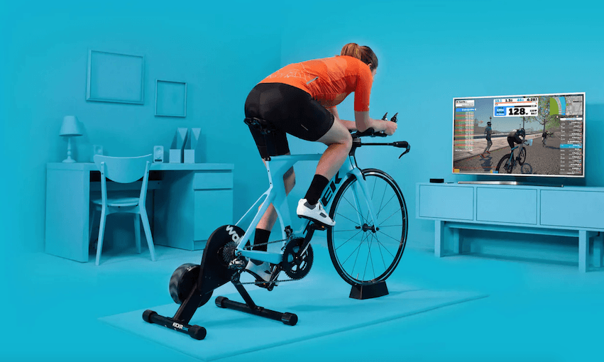 A Zwift promo image showing a road bike mounted on a smart trainer 
