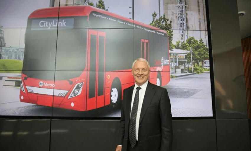 Auckland mayor Phil Goff in February, with a picture of the sort of electric bus that has now been delayed (Auckland Transport) 

