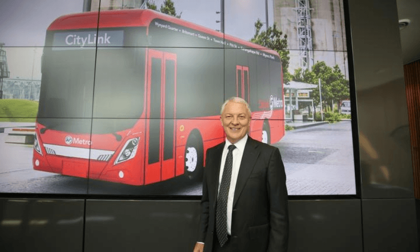 Auckland mayor Phil Goff in February, with a picture of the sort of electric bus that has now been delayed (Auckland Transport)