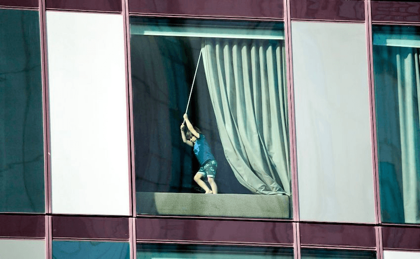 A boy pulls a curtain closed in an inner-city isolation hotel in Melbourne, March 30, 2020. (Photo: WILLIAM WEST/AFP via Getty Images) 
