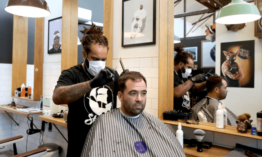 A barber in Auckland wearing a face mask while working at alert level two (Getty Images)  
