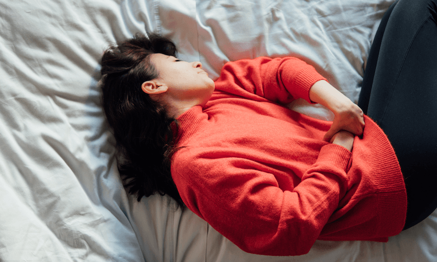 woman lying on bed in pain