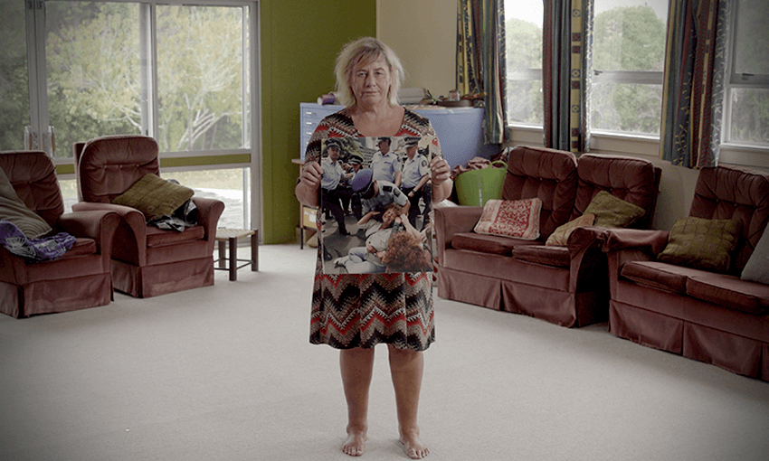 Sue Bradford holding the now-infamous photo of her in a choke hold by a police officer. Kōtare Trust, Wellsford, 2020. (Photo: On the Rag) 
