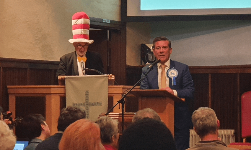 a man with a national party rosette standing next to someone with a cat in the hat hat