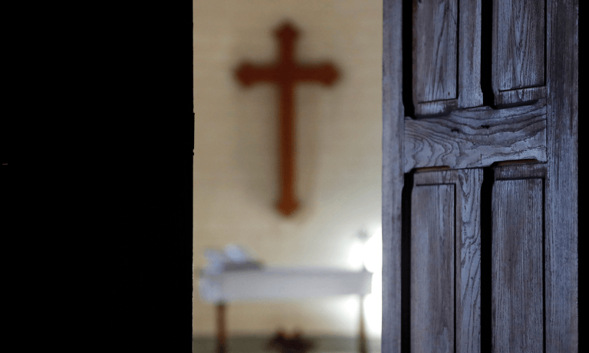 A open door in a church showing a cross in the background