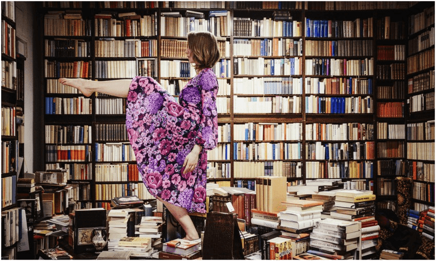 woman dances on stacks of books in library