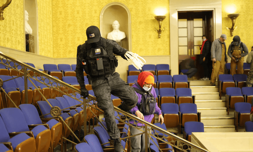 A masked man carrying zip-tie handcuffs in the Senate Chamber on January 06, 2021, during the riot inside the US Capitol in Washington, DC.(Photo: Win McNamee/Getty Images) 
