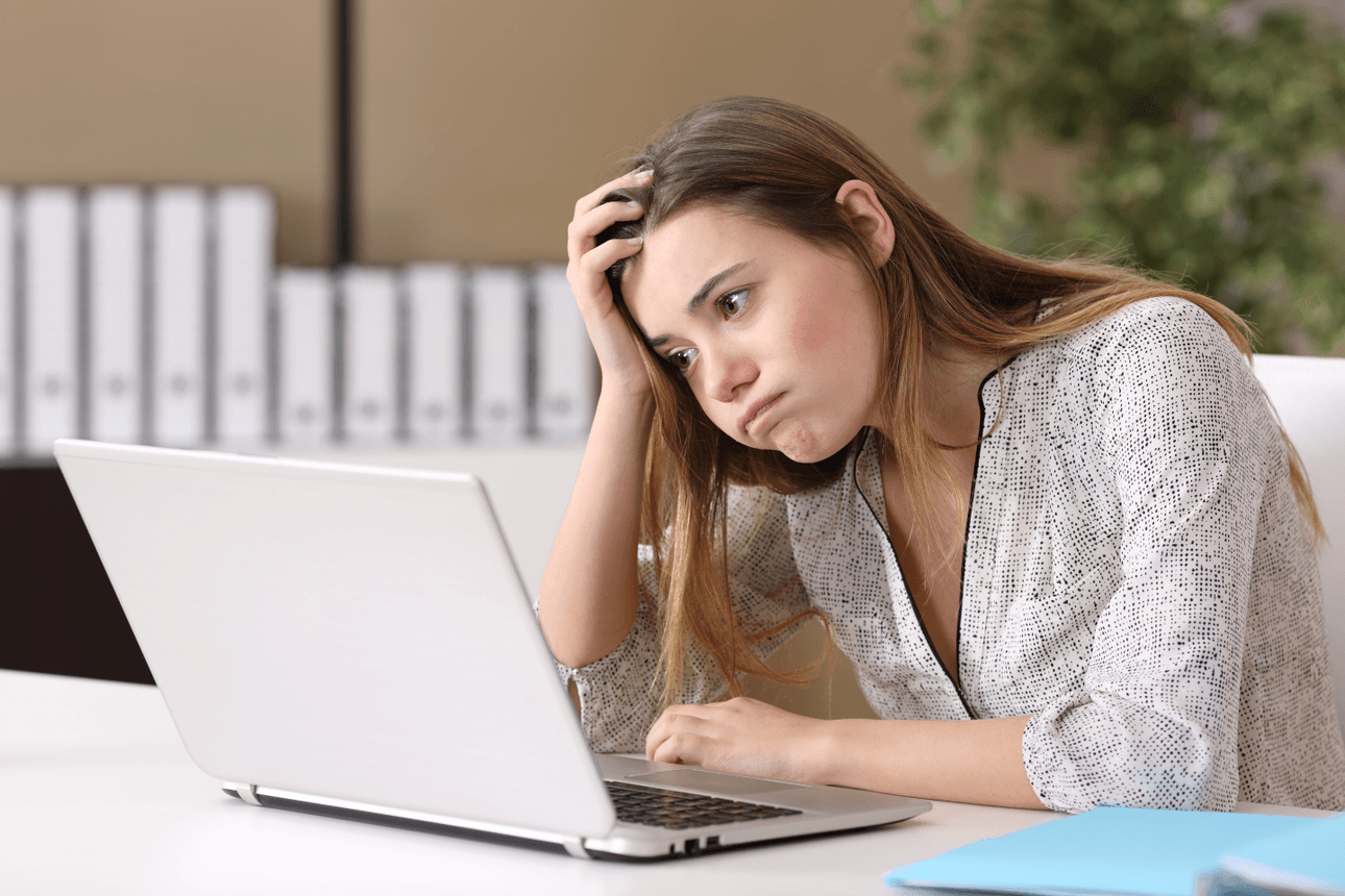 white woman frowns at a bland laptop with some plants, looking frustrated and concerned