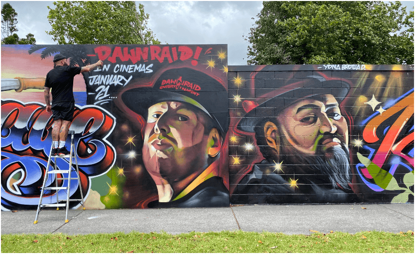 A portrait of a well-known Auckland street artist, with some of their artwork in the background.