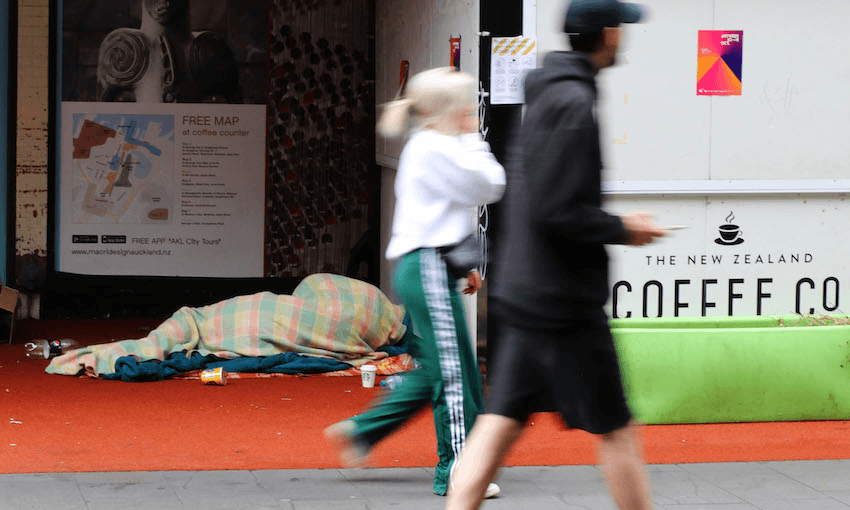 Pedestrians walk past a person rough sleeping on High Street in central Auckland in October 2020 (Photo: Lynn Grieveson/Getty Images 
