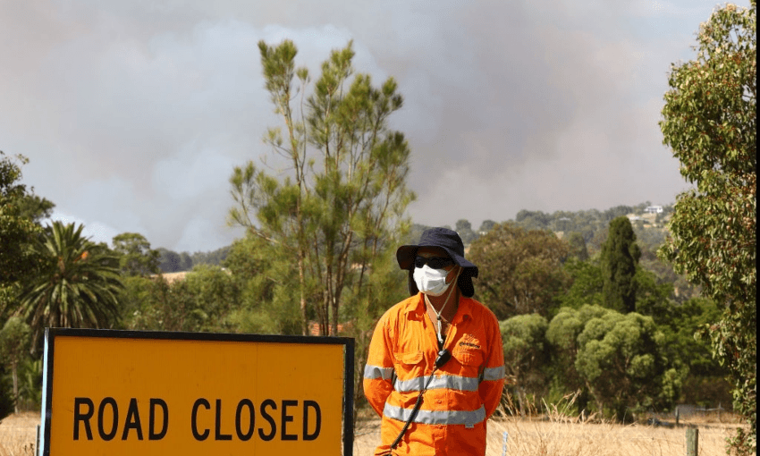 An emergency services worker standing in front of a cloud of smoke from the Western Australia fires. (Getty Images) 
