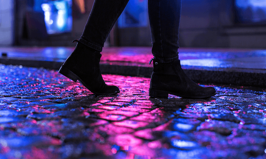 Woman in black shoes walking through the city street in the night