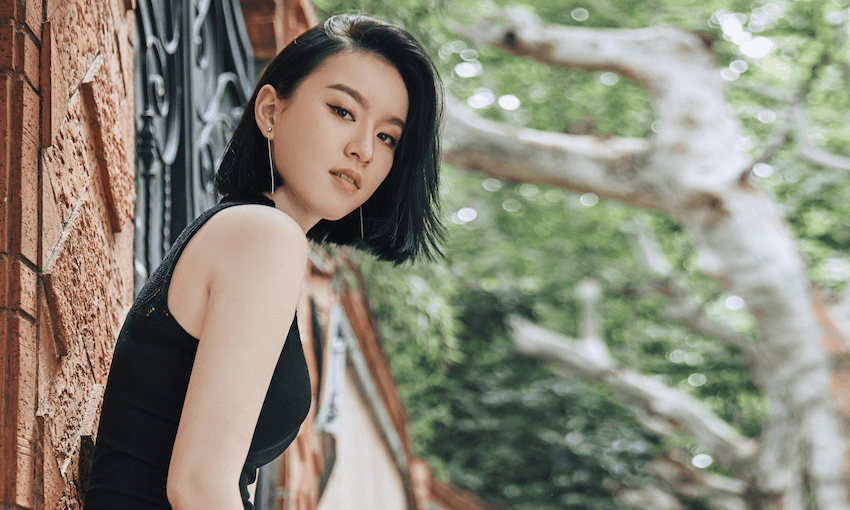 A photograph of Chloe Gong, looking to camera, with trees in the background