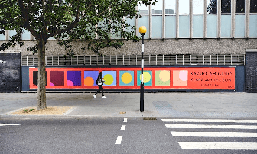 A photograph of a zebra crossing and a very long billboard for Kazuo Ishiguro's novel Klara and the Sun