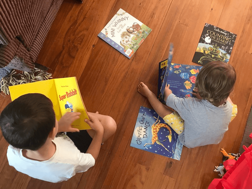 Two young children, photographed from above, surrounded by picture books