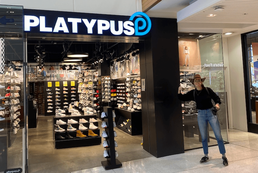 Author wearing cork hat pulls thumbs up outside Platypus in St Lukes mall