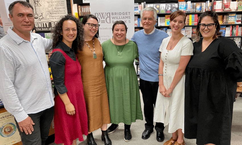 Seven people photographed together in a bookstore, happy