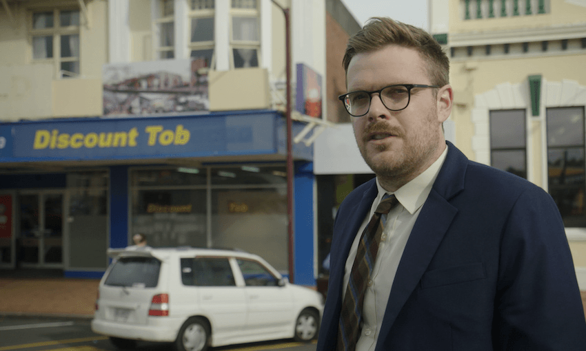 Guy Williams stands, bewildered, outside Feilding’s ‘Discount Tob’ in the second season of NZ Today. (Photo: Three)
