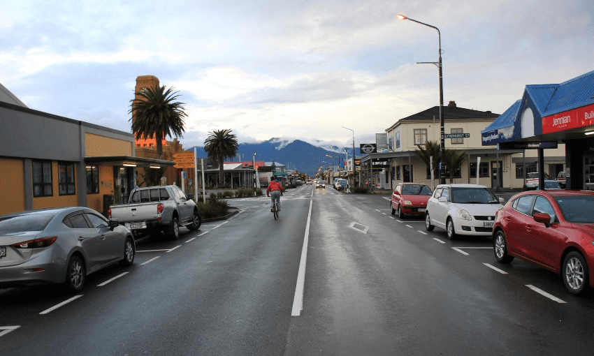 a grey street with cars parked on each side. Very flat, no high-rise buildings