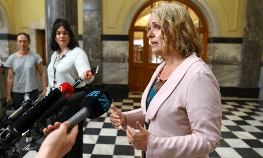 woman in a ligh pink blazer speaking on the black and white parliament tiles