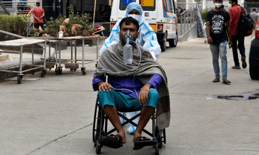 A PPE-clad worker and a man getting oxygen treatment in Kolkota, India, April 2021 (Getty Images)