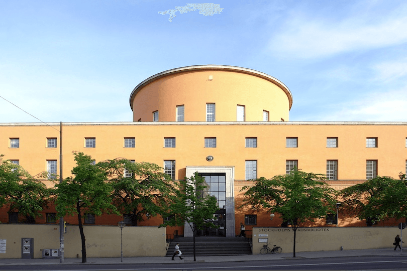 Exterior of a beautiful building, a cylinder structure on top of a rectangle, lots of windows. 