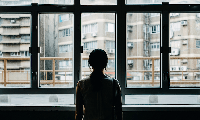 Rear view of woman looking out to city through window