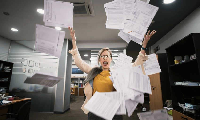 A white woman in an office throwing paperin the air