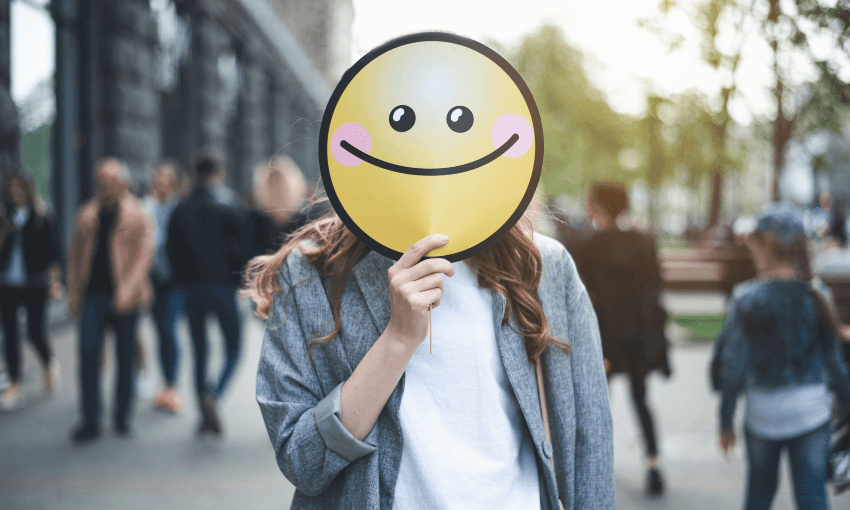 Woman holding smiling sign on her face outside smile street