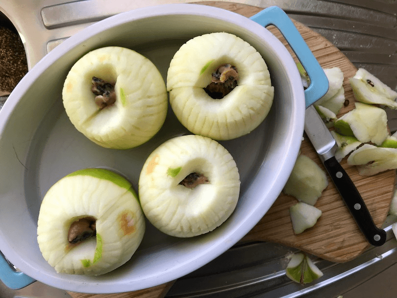 Peeled apples stuffed with dried fruit, in a baking dish