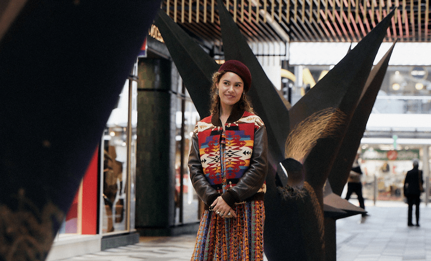 Jade Townsend stands in front of her works at Commercial Bay’s Whānau Marama exhibit (Photo: Holly Burgess)