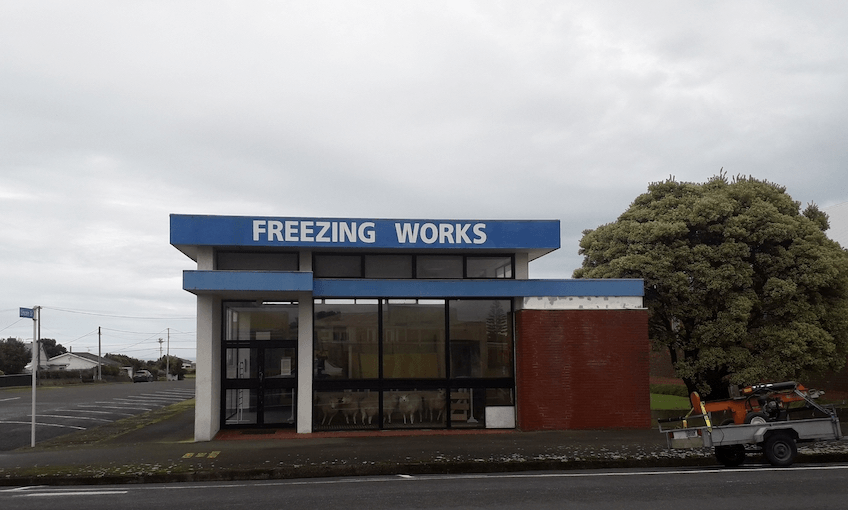 Photograph of a grey day in Pātea, view of an old building with FREEZING WORKS painted on the side