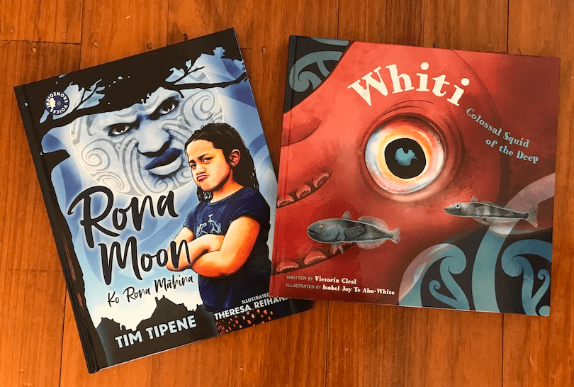 Two picture books, Rona Moon and Whiti, on a wooden floor