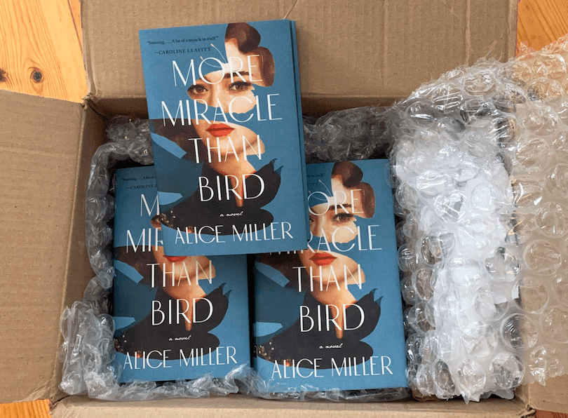 A cardboard box, bubble wrap - inside we see copies of a hardback novel 