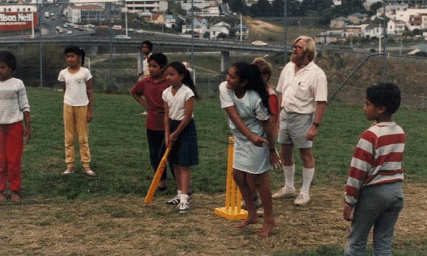 Photo of primary school kids playing cricket with those yellow plastic bat and wickets, a school playing field, a teacher in walk shorts