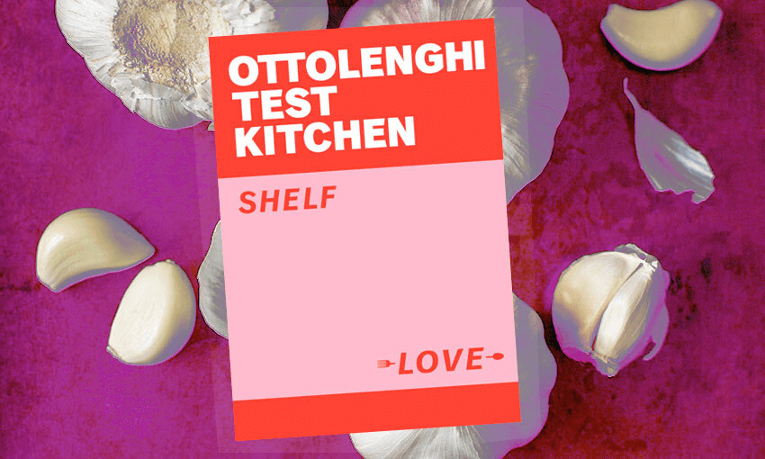 A purple background strewn with huge garlic cloves and full bulbs; on top a copy of Ottolenghi's Test Kitchen, a bright pink and red design triumph.