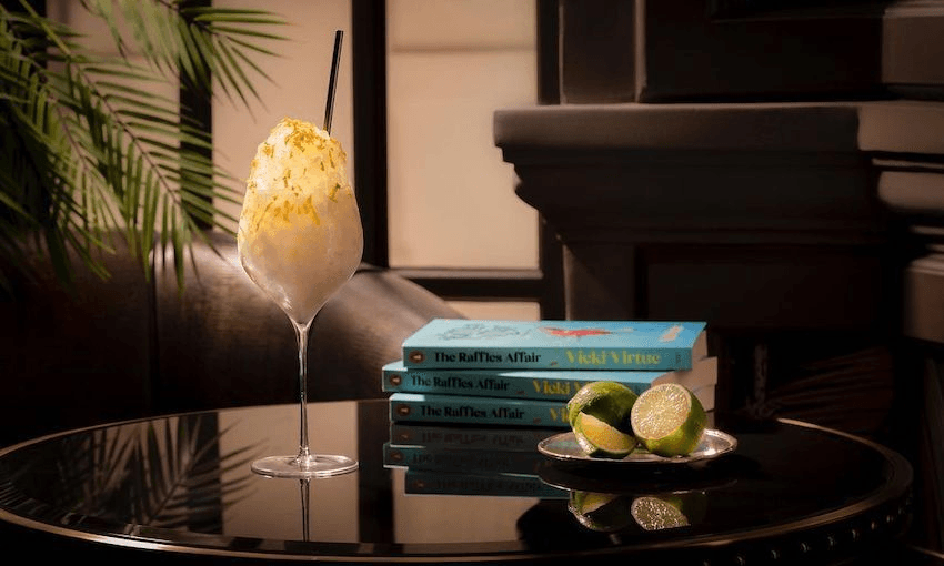 Photo of a posh cocktail beside a pile of books, and a dish of cut limes. All very tasteful and expensive looking. 