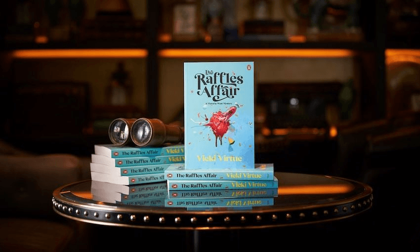 Photo of a pile of books, one stood up so we can see the cover. Setting is a gloomy library.