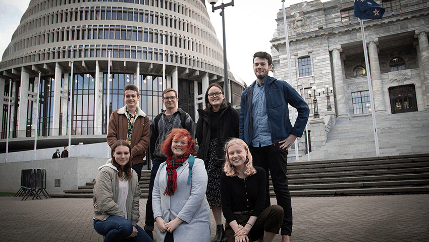 a group of smiling young people in front of the beehive