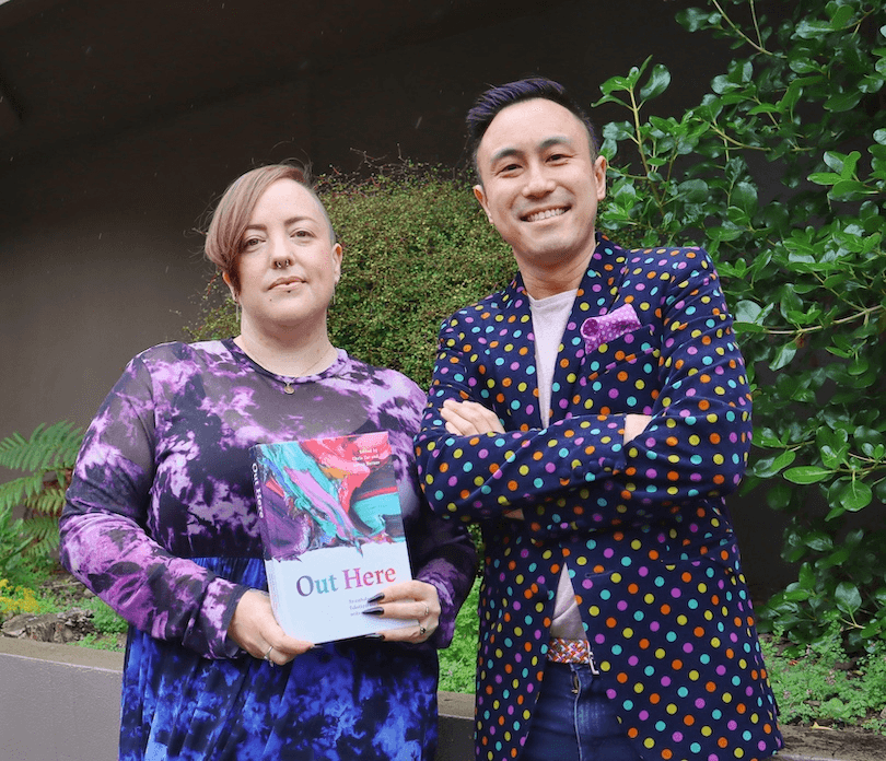 Two radiant poets, dressed in purple finery, holding a copy of their new book. 