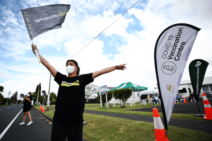 A woman wearing a respirator mask moves a Whānau O Waipareira outside a Covid-19 vaccination centre.